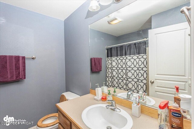 bathroom with walk in shower, vanity, and toilet