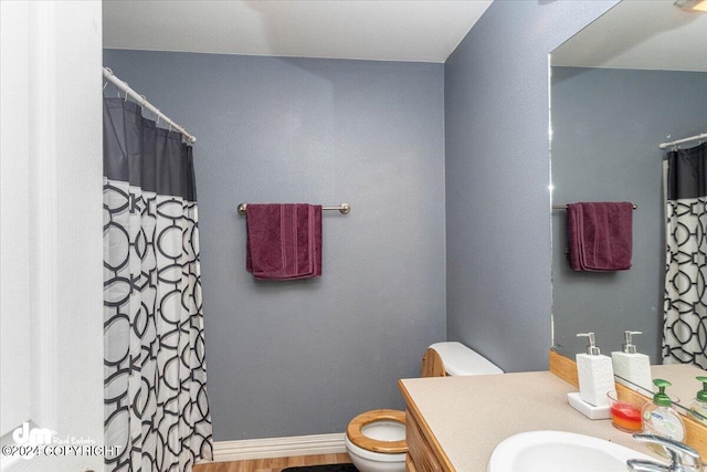 bathroom featuring walk in shower, wood-type flooring, vanity, and toilet