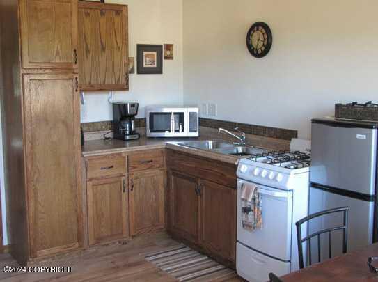 42781 Brenda Way, Soldotna, AK 99669 - kitchen featuring appliances with stainless steel finishes, wood finished floors, and brown cabinets