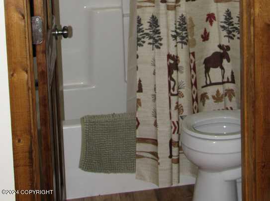 bathroom featuring shower / tub combo and toilet