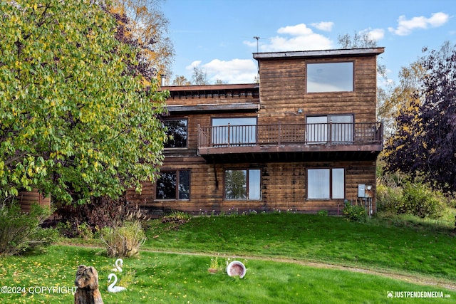 rear view of house featuring a balcony and a yard