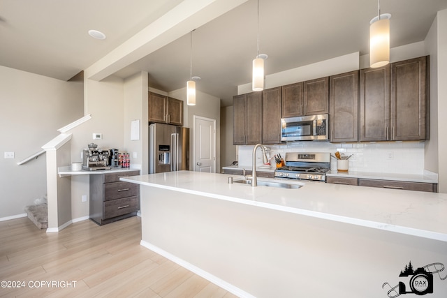 kitchen with dark brown cabinetry, decorative backsplash, stainless steel appliances, light countertops, and a sink