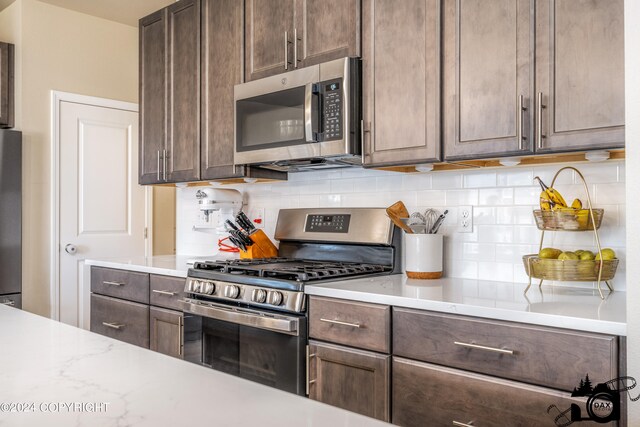 kitchen featuring stainless steel appliances, dark brown cabinetry, and backsplash