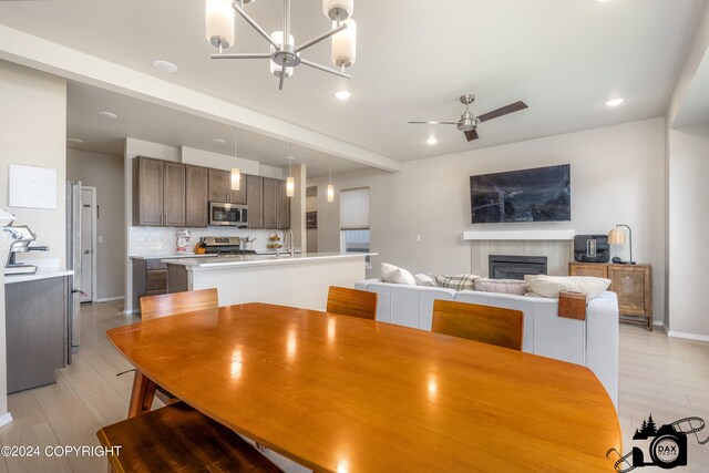 dining area with light wood-type flooring, a fireplace, a ceiling fan, and recessed lighting