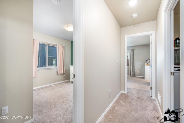 hallway with carpet floors, visible vents, and baseboards