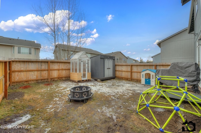 view of yard featuring an outdoor fire pit, a fenced backyard, an outdoor structure, and a storage unit