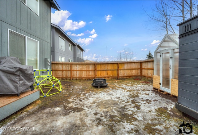 view of yard with a greenhouse, fence, a fire pit, and an outdoor structure