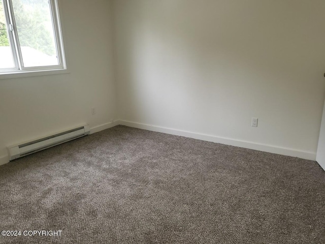 carpeted empty room with a baseboard heating unit