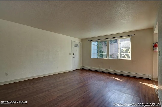 spare room with a textured ceiling, baseboard heating, and dark wood-type flooring