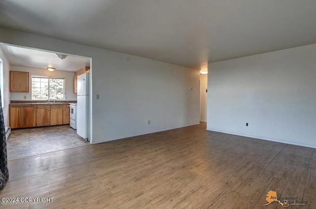 unfurnished living room with sink and light hardwood / wood-style floors