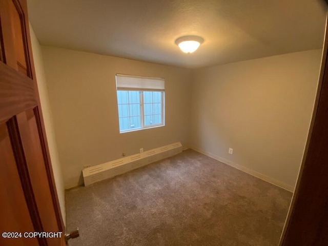 empty room featuring carpet floors and a baseboard heating unit