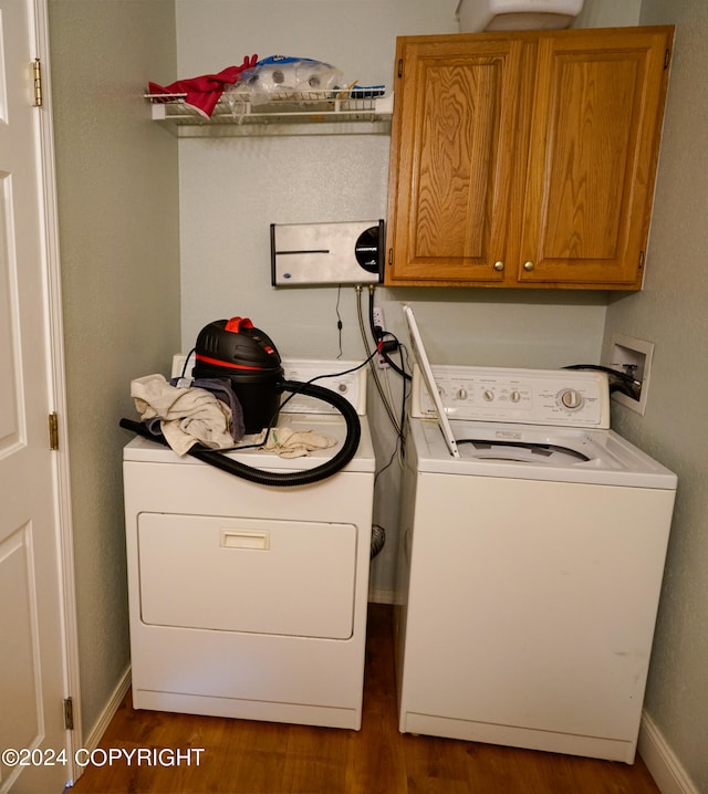 laundry area with cabinets, dark hardwood / wood-style flooring, and washing machine and dryer