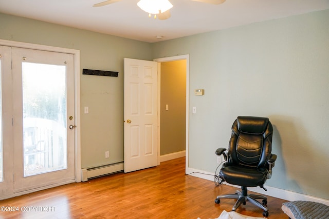 living area with light hardwood / wood-style floors, baseboard heating, and ceiling fan