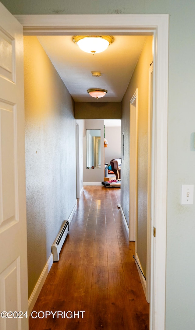 hall with dark wood-type flooring and a baseboard heating unit