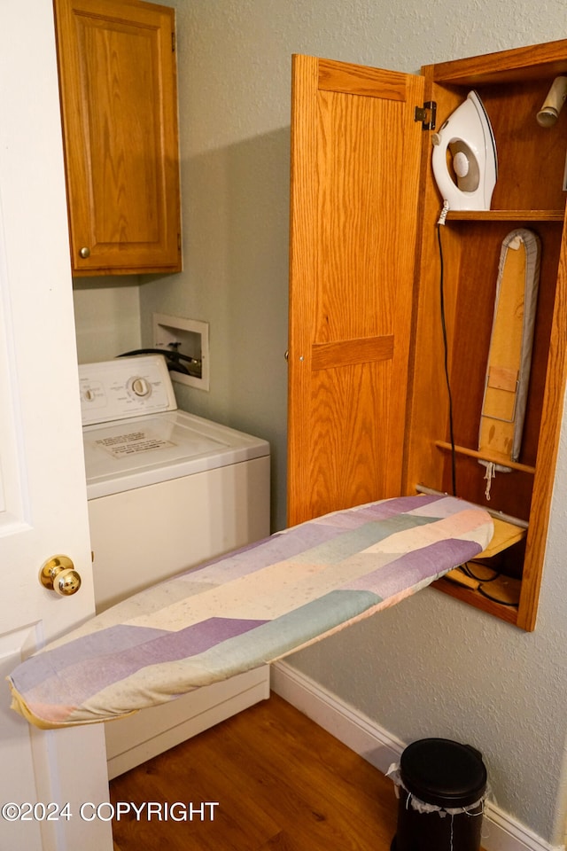 washroom with dark wood-type flooring, washer / dryer, and cabinets