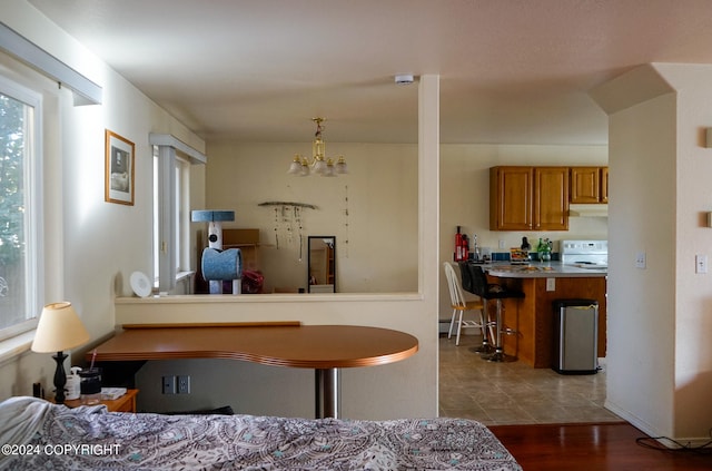 interior space featuring pendant lighting, white stove, a kitchen bar, an inviting chandelier, and dark hardwood / wood-style floors