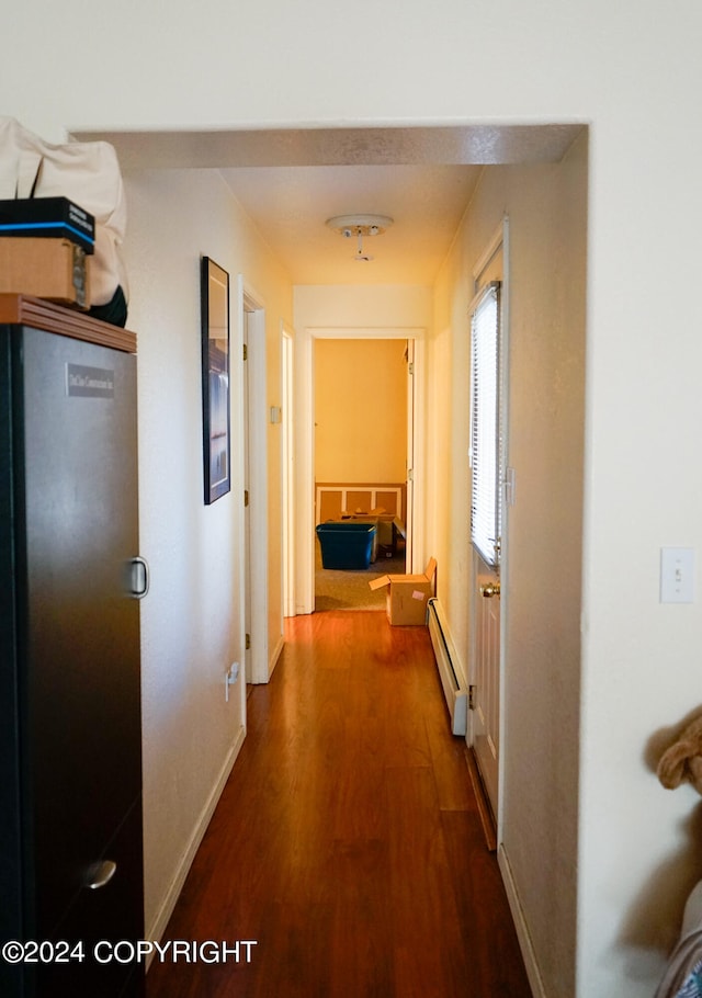 corridor featuring hardwood / wood-style floors and a baseboard heating unit