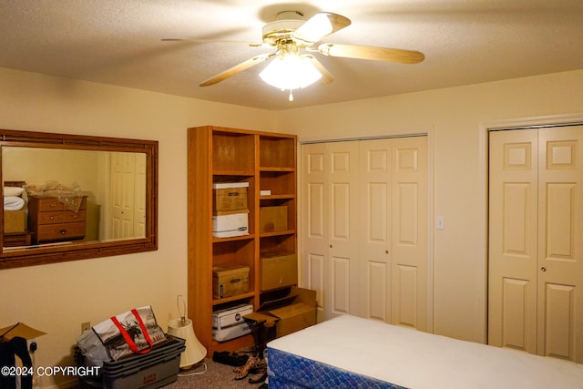 carpeted bedroom featuring ceiling fan, multiple closets, and a textured ceiling