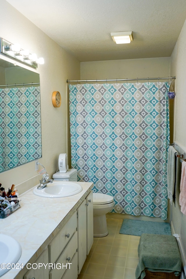 bathroom with tile patterned flooring, a textured ceiling, vanity, and toilet