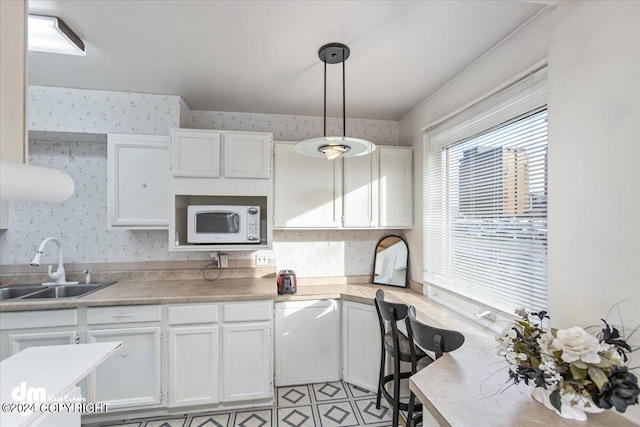 kitchen with light tile patterned floors, white cabinets, decorative light fixtures, and sink