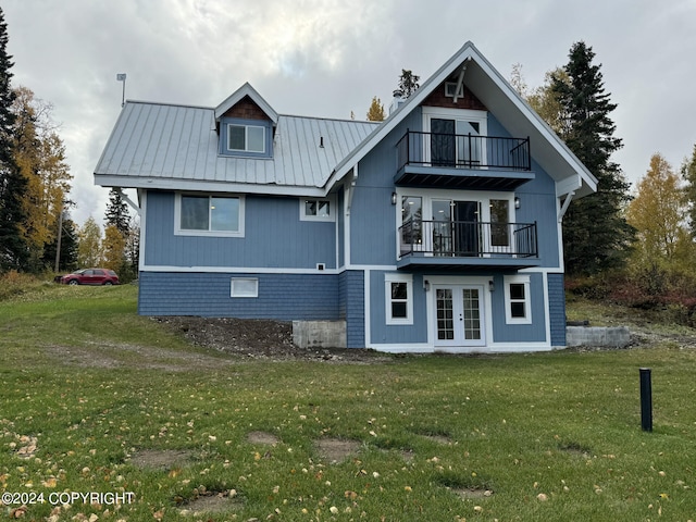 rear view of property featuring a yard, a balcony, and french doors