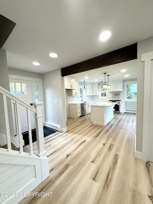 kitchen featuring a kitchen island, decorative light fixtures, white cabinetry, appliances with stainless steel finishes, and light wood-type flooring