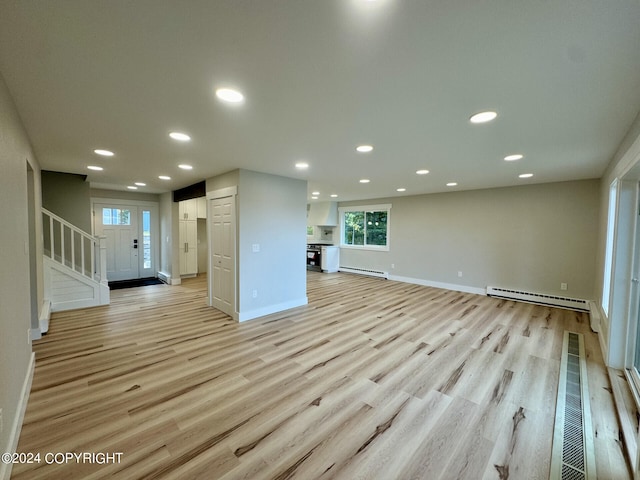 unfurnished living room with light wood-type flooring and a baseboard radiator