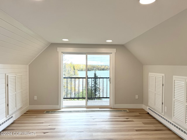 additional living space featuring light hardwood / wood-style flooring, a water view, baseboard heating, and vaulted ceiling