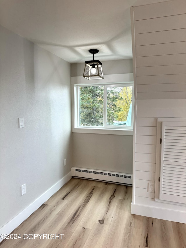 unfurnished dining area with a baseboard heating unit and light hardwood / wood-style flooring