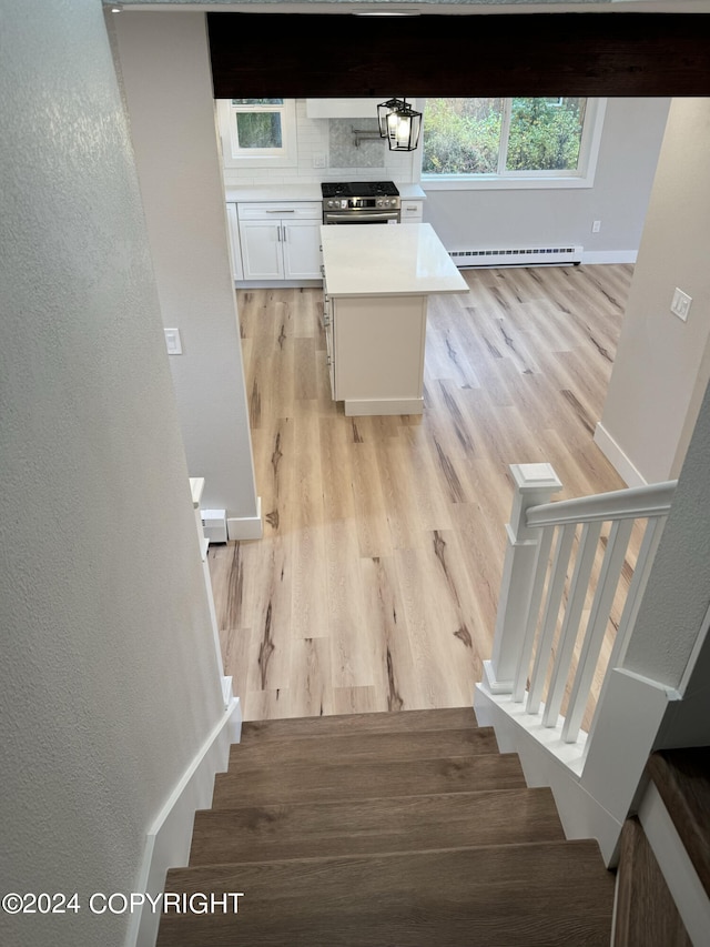 stairs with a baseboard heating unit and wood-type flooring