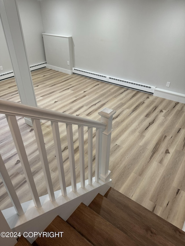 stairway featuring hardwood / wood-style floors and a baseboard heating unit