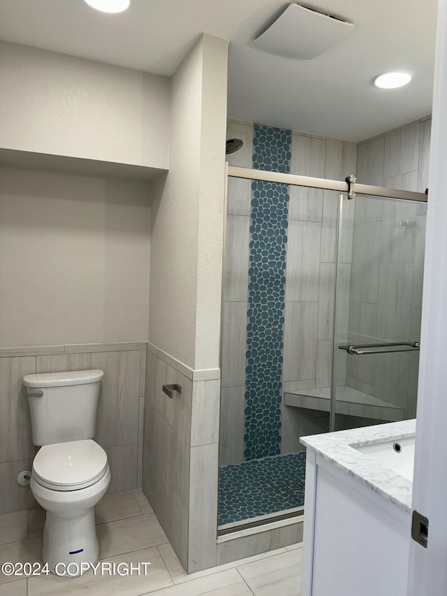 bathroom featuring vanity, a shower with shower door, and toilet