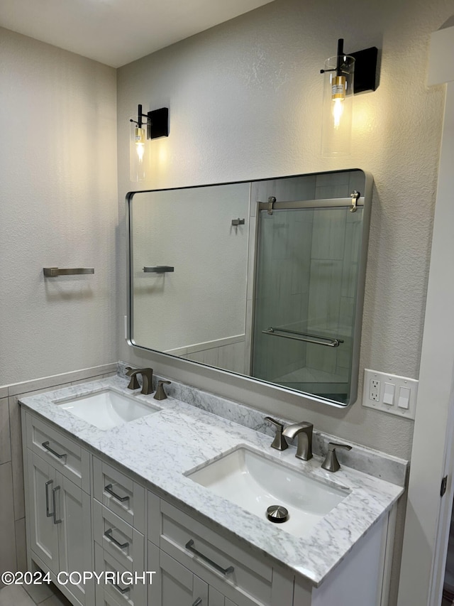 bathroom featuring a shower with shower door and vanity