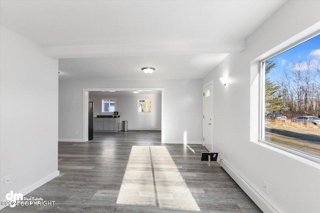 hall with a baseboard heating unit, a healthy amount of sunlight, and dark hardwood / wood-style flooring