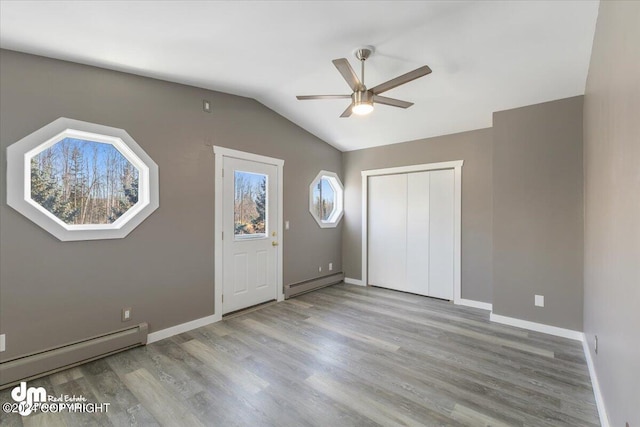 interior space with light hardwood / wood-style flooring, baseboard heating, lofted ceiling, and ceiling fan