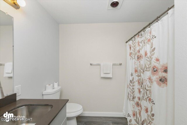 bathroom featuring vanity, a shower with shower curtain, hardwood / wood-style flooring, and toilet