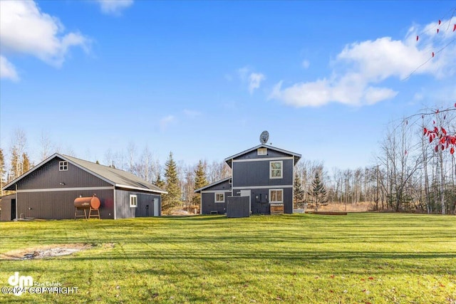 back of house with an outdoor structure and a yard