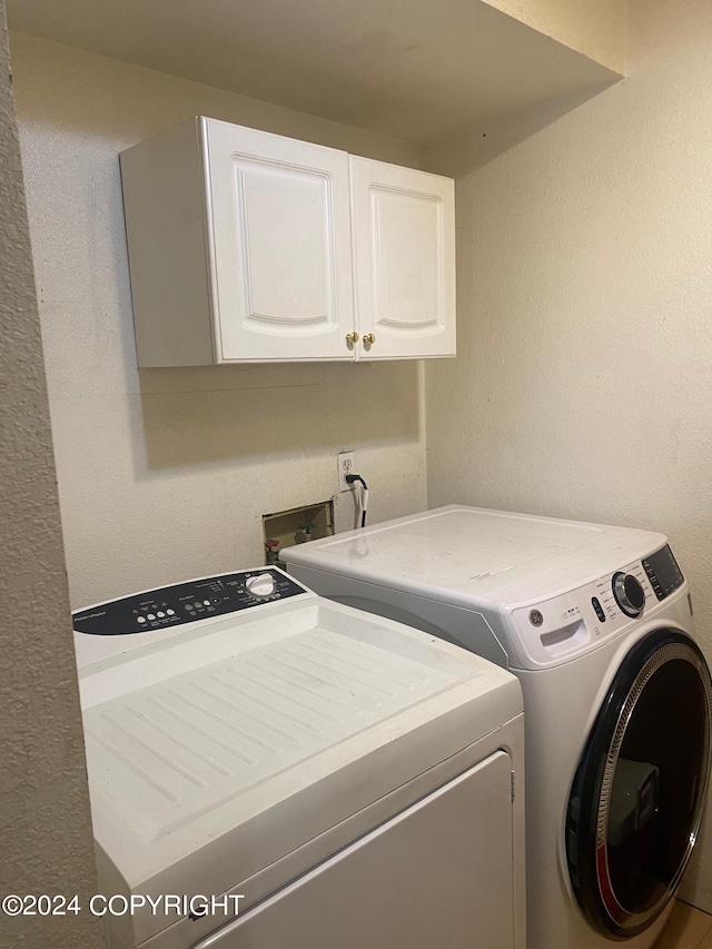 washroom featuring cabinets and washer and clothes dryer