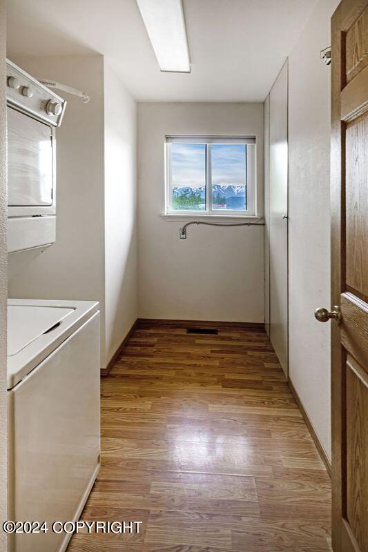 laundry room with light wood-type flooring and stacked washing maching and dryer