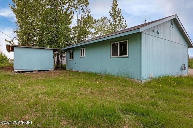 back of property with a lawn and a storage unit