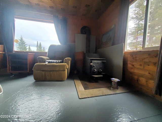 sitting room with concrete floors, a healthy amount of sunlight, and a wood stove