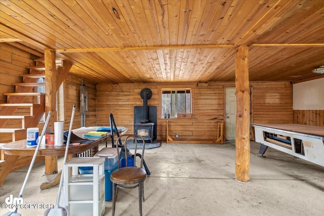 interior space with wooden walls, wooden ceiling, and a wood stove