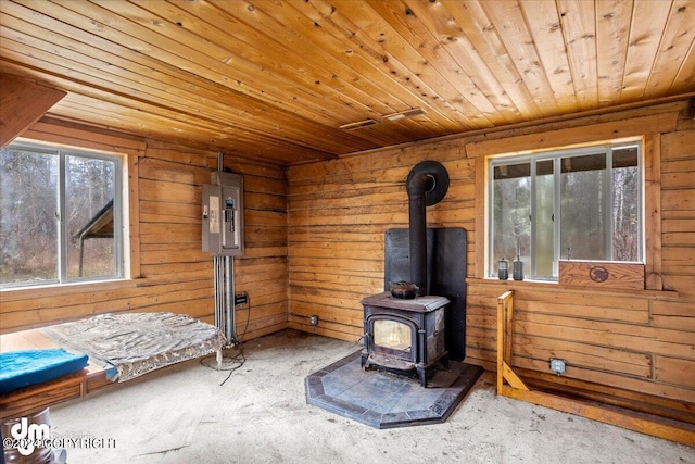 interior space with a wood stove, electric panel, wood ceiling, and wood walls