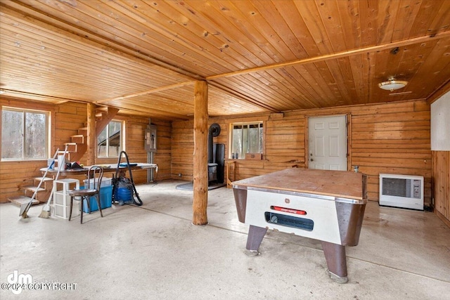 rec room with heating unit, wood walls, wooden ceiling, a wood stove, and electric panel