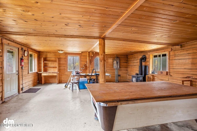 playroom with concrete flooring, wooden walls, a wood stove, and wood ceiling