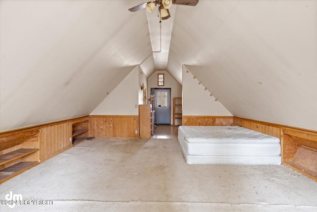 additional living space with lofted ceiling, wooden walls, and light carpet