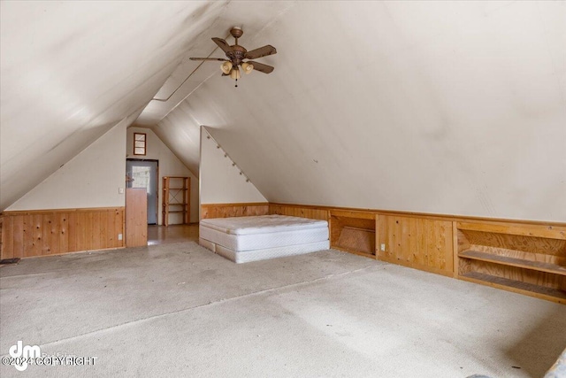 additional living space featuring lofted ceiling, a wainscoted wall, wooden walls, carpet flooring, and ceiling fan