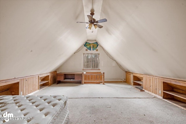 additional living space with lofted ceiling, wooden walls, and light colored carpet