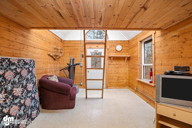 living area with lofted ceiling with skylight, wood ceiling, and wood walls