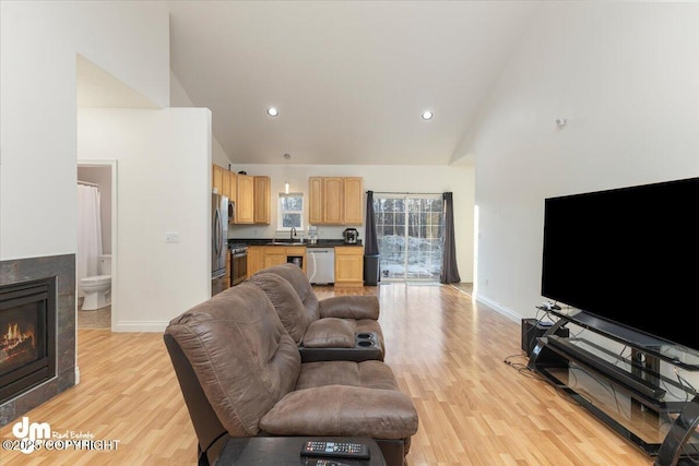 living room featuring sink, high vaulted ceiling, and light wood-type flooring